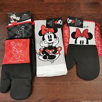 Top view of the kitchen set including two kitchen towels with Minnie Mouse, two large oven mitts with Minnie Mouse and Mickey Mouse, and a large oven mitt and pot holder with Minnie Mouse