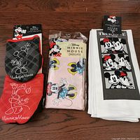 Full set including oven mitts, towels, and vinyl tablecloth on wooden surface, showing designs and packaging