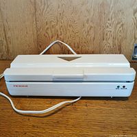 Front view of closed white Rossi vacuum sealer with power cord.