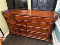 Front view of wooden dresser showing multiple drawers and brass hardware.