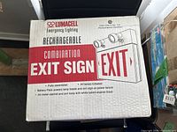 Photo of the boxed Lumacell rechargeable combination exit sign showing box details and labeling.