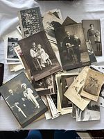 Overview of large assortment of vintage black and white photographs, some mounted on cardstock, featuring various individuals including children and adults.