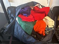 Large black bag filled with various colorful fabric pieces including solid colors and patterned textile.