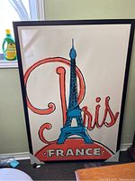 Framed Paris France print with Eiffel Tower in blue and 'Paris' in large red script letters on white background.