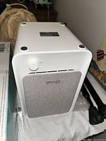 Levoit air purifier shown from the front with gray fabric panel and power button on top corner.