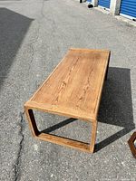Full view of the rectangular long wood coffee table showing the top wood grain finish and square frame legs.
