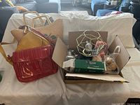 View of assorted purses and a box of household items on a couch