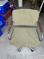 Front view of olive green fabric office chair with wooden armrests and chrome frame.