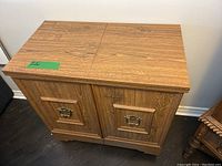 Closed view of the vintage sewing desk showing wood grain finish and double doors with brass handles.