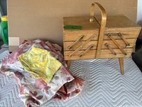 Wooden multi-tiered sewing box next to assorted colorful fabric pieces.