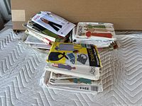 Photo showing approximately 15 vintage sewing patterns stacked on a mattress, including visible McCalls, Simplicity, and Burda brand envelopes.