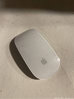 Top view of Apple Magic Mouse showing white surface with Apple logo.