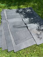 Six black rubber exercise mats laid out on grass. Some mats visible overlapping each other.