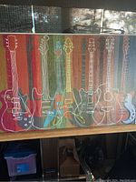 Front view of guitar print showing colorful outline of electric and acoustic guitars on wood background.