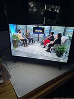 Photo of LG 32-inch LED TV showing a talk show program with four people seated and plants in the background, illustrating good screen condition and image quality.