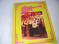 Front cover of the Monkees Fan Club Pre-Magazine booklet showing a bright yellow cover with a color photo of the band on stage playing instruments.