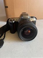 Front view of Nikon N65 camera showing attached zoom lens and camera strap.