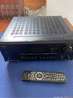 Front view of Onkyo stereo receiver on a blue surface with a remote control in front.