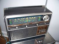 Front view of vintage Sears radio showing analog tuning dial, tuning knob, sliders, speaker grille, and power switch.