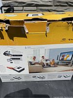 Photo of yellow box showing Sony device packaging with some box damage. Box displays product features and home use images.
