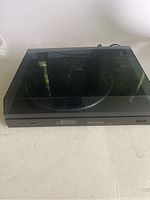 Full front view of black Vector Research turntable with dust cover down placed on flat surface.