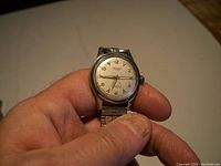 Close-up of the vintage Tegra wristwatch held in hand, showing the dial and metal band.