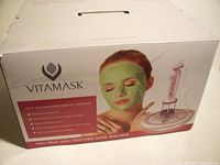Boxed Vitamask machine showing branding, image of woman with green face mask, and machine components.