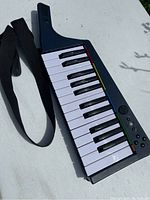 Full view of black wireless MIDI keyboard with 25 white and black keys, built-in strap, and handle extension for portability.