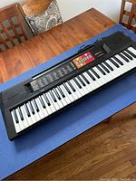 Full view of Yamaha PSR-F51 keyboard placed on a wooden table resting on a blue mat.