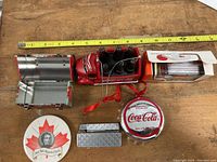 Top view of Coca Cola musical tin can delivery truck with 6 small bottles, rectangular metal tin, small metal case, round tin, and item with red strap
