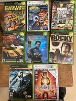 Top-down view of all 8 Xbox game cases arranged on a wooden surface.