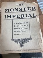 Antique song book titled 'The Monster Imperial' with visible wear, some torn edges and discoloration on cover page.