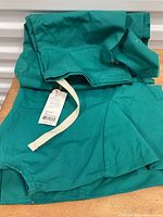 Photo of hunter green medical scrub pants showing the fabric, tags, and drawstring detail.