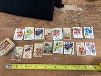 Miniature inspirational and religious cards with floral and bird illustrations, laid out with a measuring tape for size reference alongside the vintage Bayer Aspirin tin.