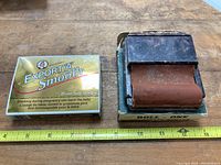 Vintage Roll-One metal cigarette roller with a worn brown roller placed on its original box, next to a Macdonald Export 'A' Smooth tobacco pack.