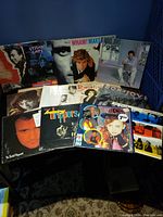 Six vinyl records from the 1980s with visible album covers such as Wham! and Culture Club, arranged on a dark surface