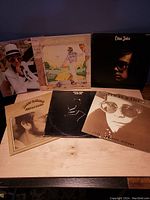 Six Elton John vinyl albums displayed in two rows, showing original album covers with various portraits and illustrations of Elton John.