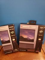 Front view of two Monster HDMI cables boxes against a blue background, showing cable lengths 4 ft and 12 ft and 4K HDR support.