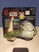 Front view of the packaged Jabba the Hutt figure showing figure, small container and card inside blister pack with Episode 1 branding.