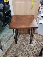 Full view of the oak veneer side table showing the top pattern and metal hairpin legs