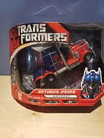 Front of the box with Optimus Prime in truck mode visible through plastic window. Box with Transformers logo and 'Optimus Prime Autobot' label.
