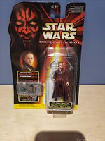 Front view of Star Wars Episode I Queen Amidala action figure in original sealed packaging, showing the figure in purple attire with detailed cardboard backing featuring Darth Maul's imagery.
