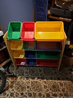 Full view of wooden shelf unit holding 16 plastic bins in multiple colors.