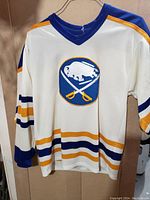 Front view of white vintage Buffalo Sabres hockey jersey with the team logo and colored stripes on sleeves and torso.