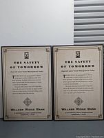 Photo of two Walker Ridge Bank promotional boards side by side against a white wall with storage unit door visible. Both boards contain identical printed text and graphics about bank safety and management.