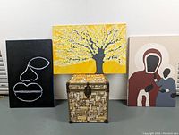 Photo showing all three paintings and a decorative box on the floor for scale and context.