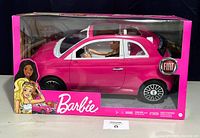Pink Barbie Fiat model car with Barbie doll seated inside, viewed from left front side in original box.