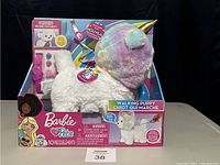 Front view of the Barbie Walk & Wag Puppy Unicorn doll in original box, showing product branding, unicorn hood, and included accessories.