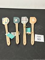 Four bunny-themed silicone spatulas with wooden handles laid flat, showing each unique bunny design.