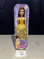 Front view of boxed Disney Princess Belle doll standing in packaging with visible branding and yellow dress.